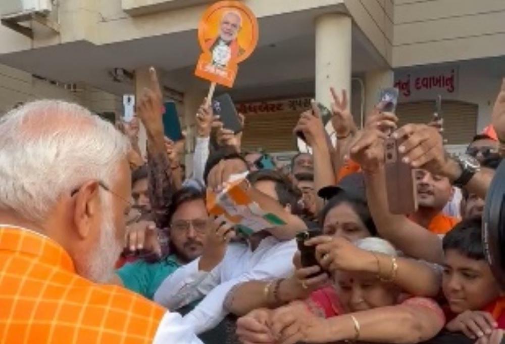 The Weekend Leader - Woman Ties Rakhi To PM Modi As Huge Crowd Gathers Outside Polling Booth In Ahmedabad